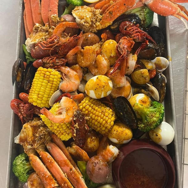 A large Cajun seafood boil platter with crab legs, shrimp, crawfish, mussels, corn, potatoes, and eggs.