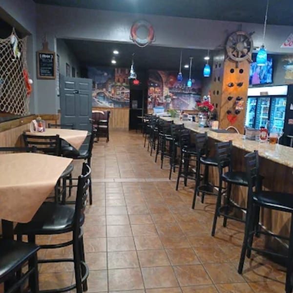 Interior of Cajun Crab restaurant with bar seating, dining tables, and nautical decor.