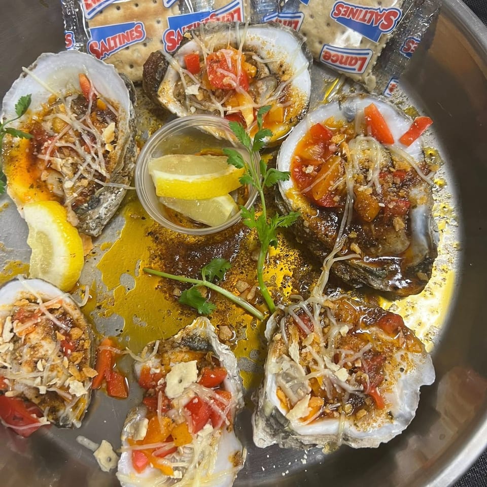 Cajun Crab's baked oysters topped with cheese, peppers, and herbs, served with lemon and crackers.